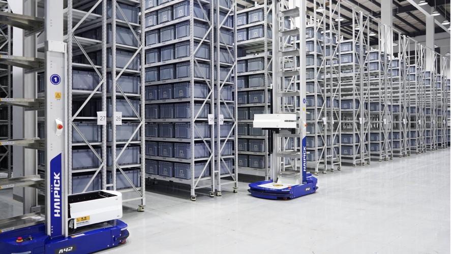 Blue picking robots with tote lifts working between rows of storage shelving